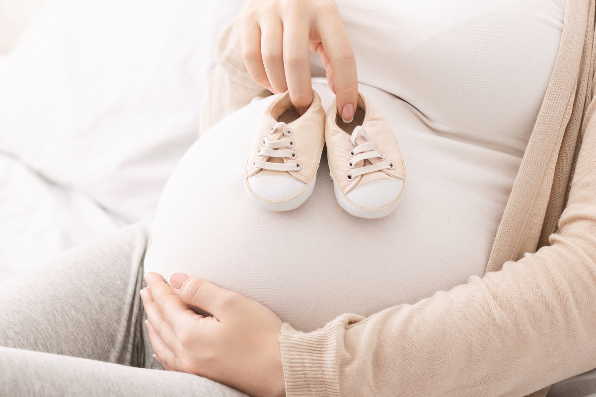 femme enceinte tenant chaussons bébé